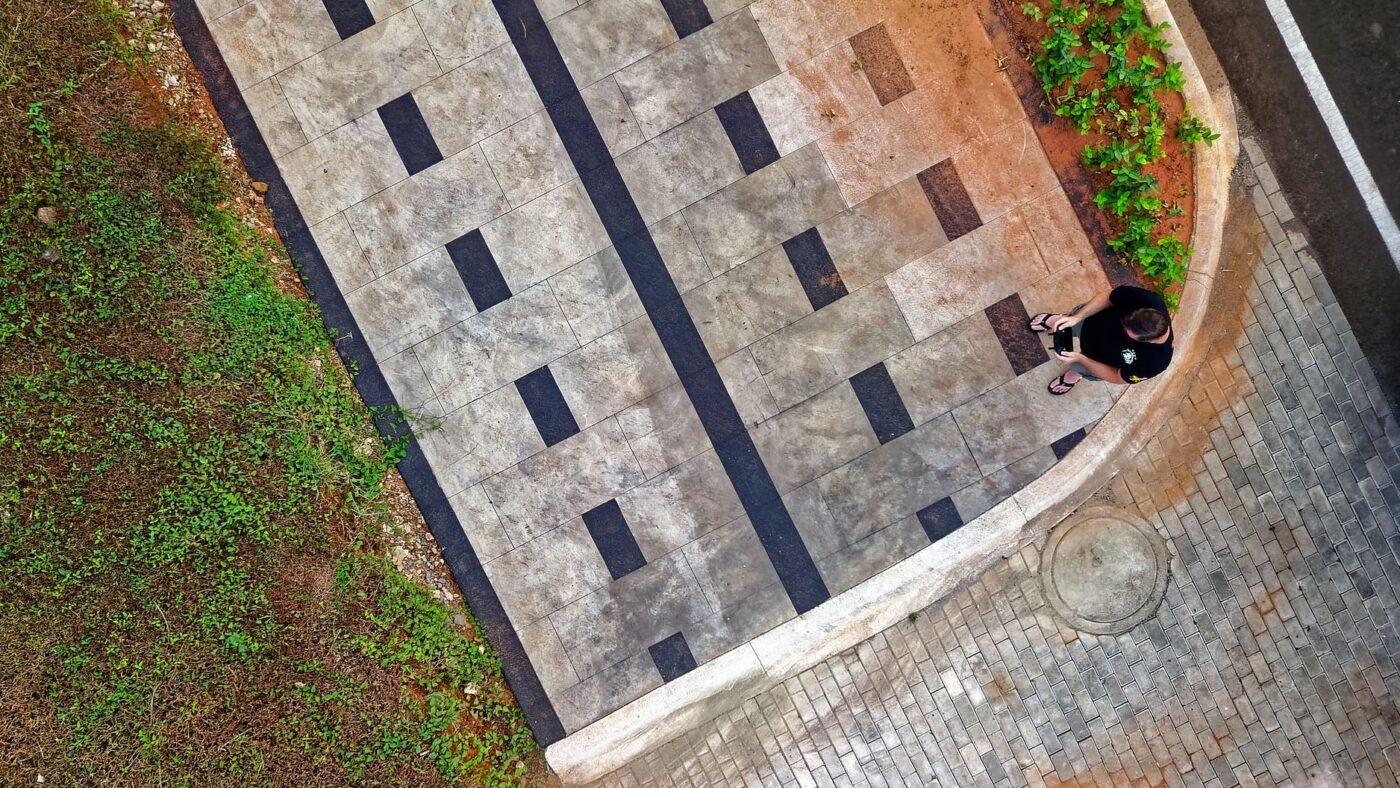 Aerial view of a walkway paved with large format gray slabs and dark accent strips, the look 24x24 pavers create