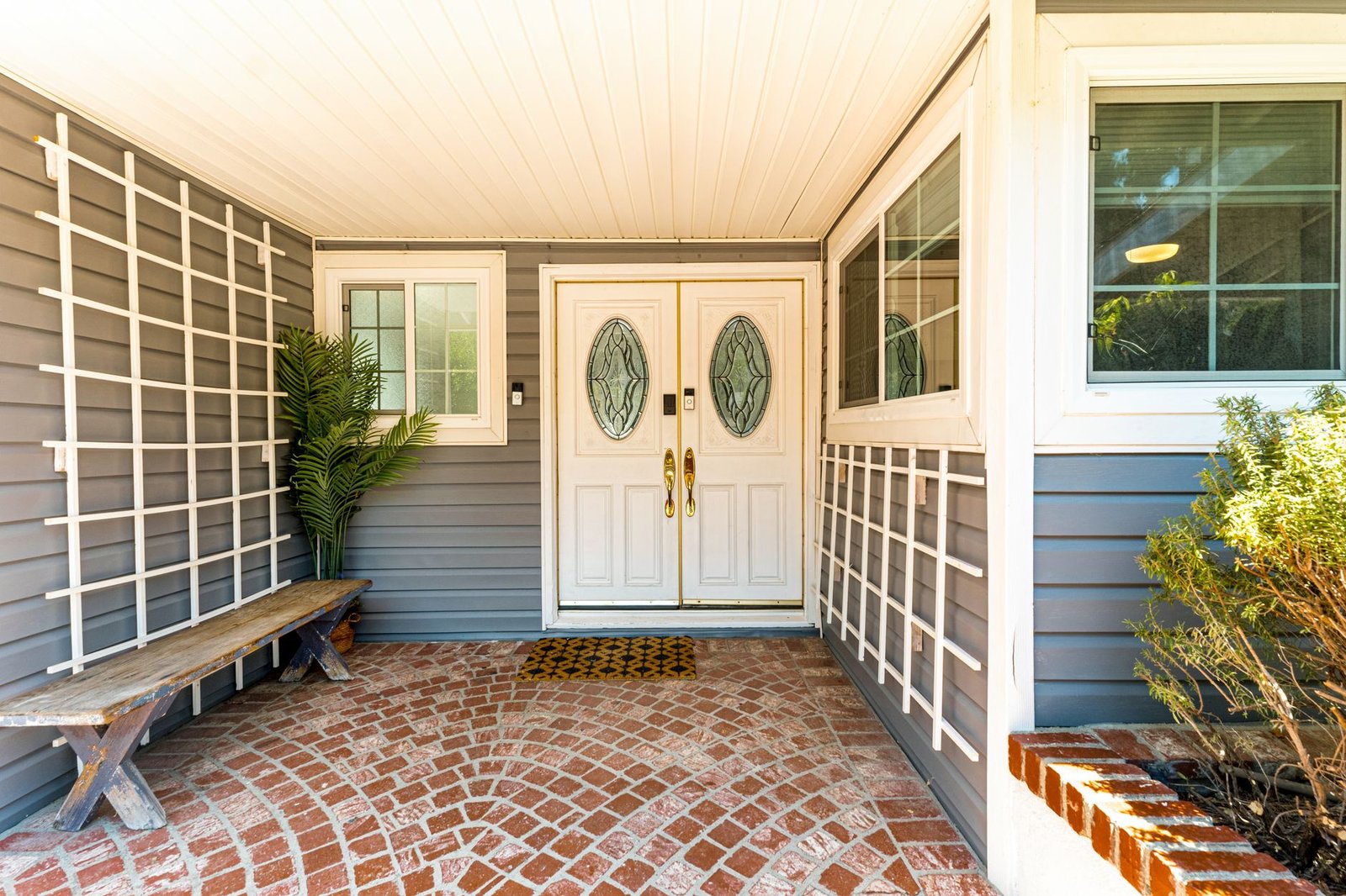 Brick entry porch with pavers laid in overlapping fan-shaped arcs leading to a double front door