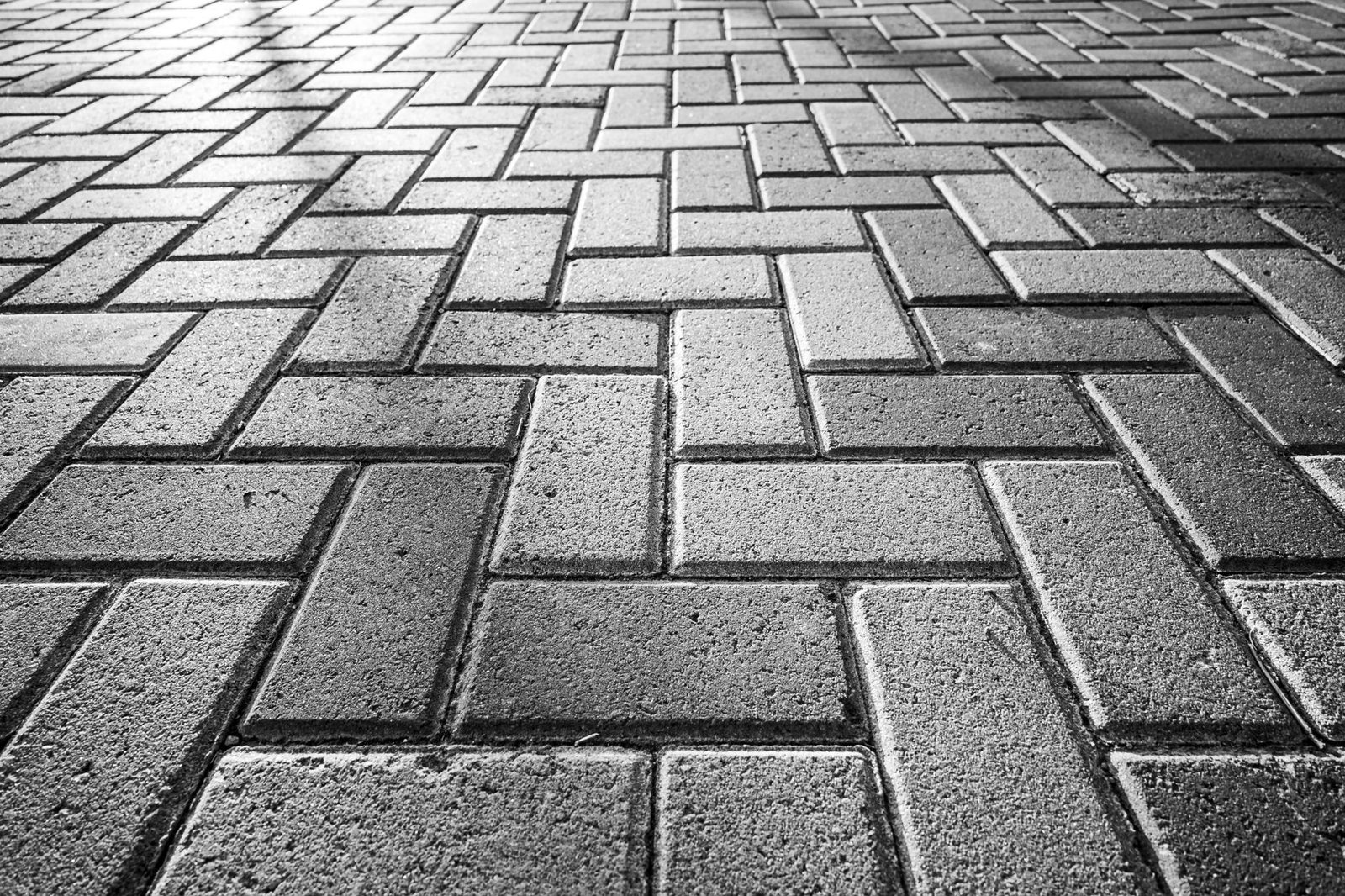 Close-up of gray concrete pavers in a herringbone pattern with tight, even joints after compacting