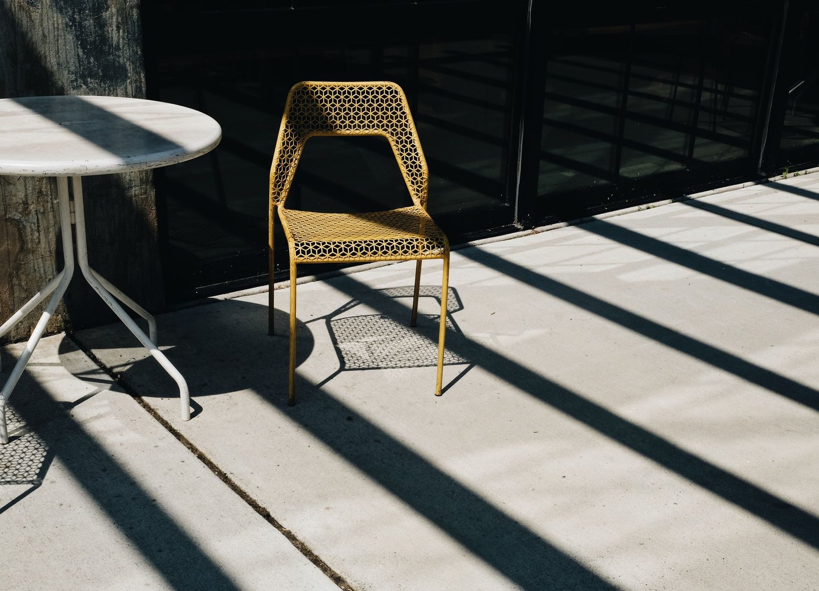 Plain concrete patio slab with a saw-cut control joint and a chair casting shadows across it