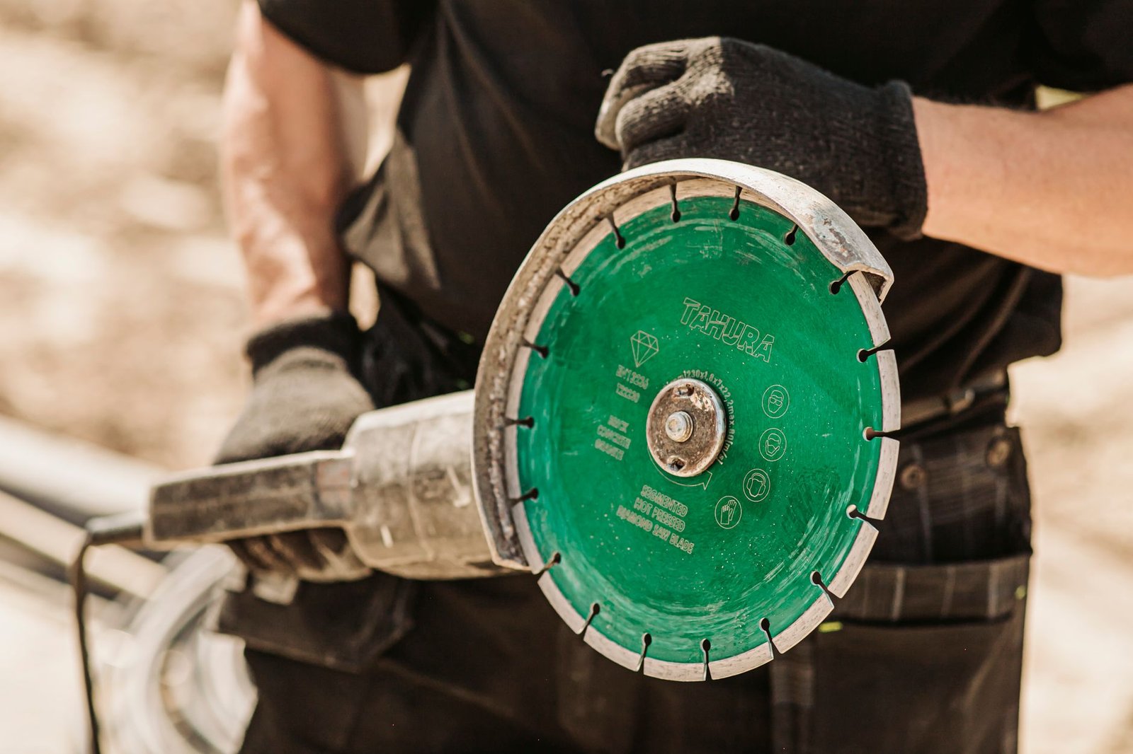 Close-up of a segmented diamond blade mounted on a large grinder, with slots between the segments for cooling and clearing debris
