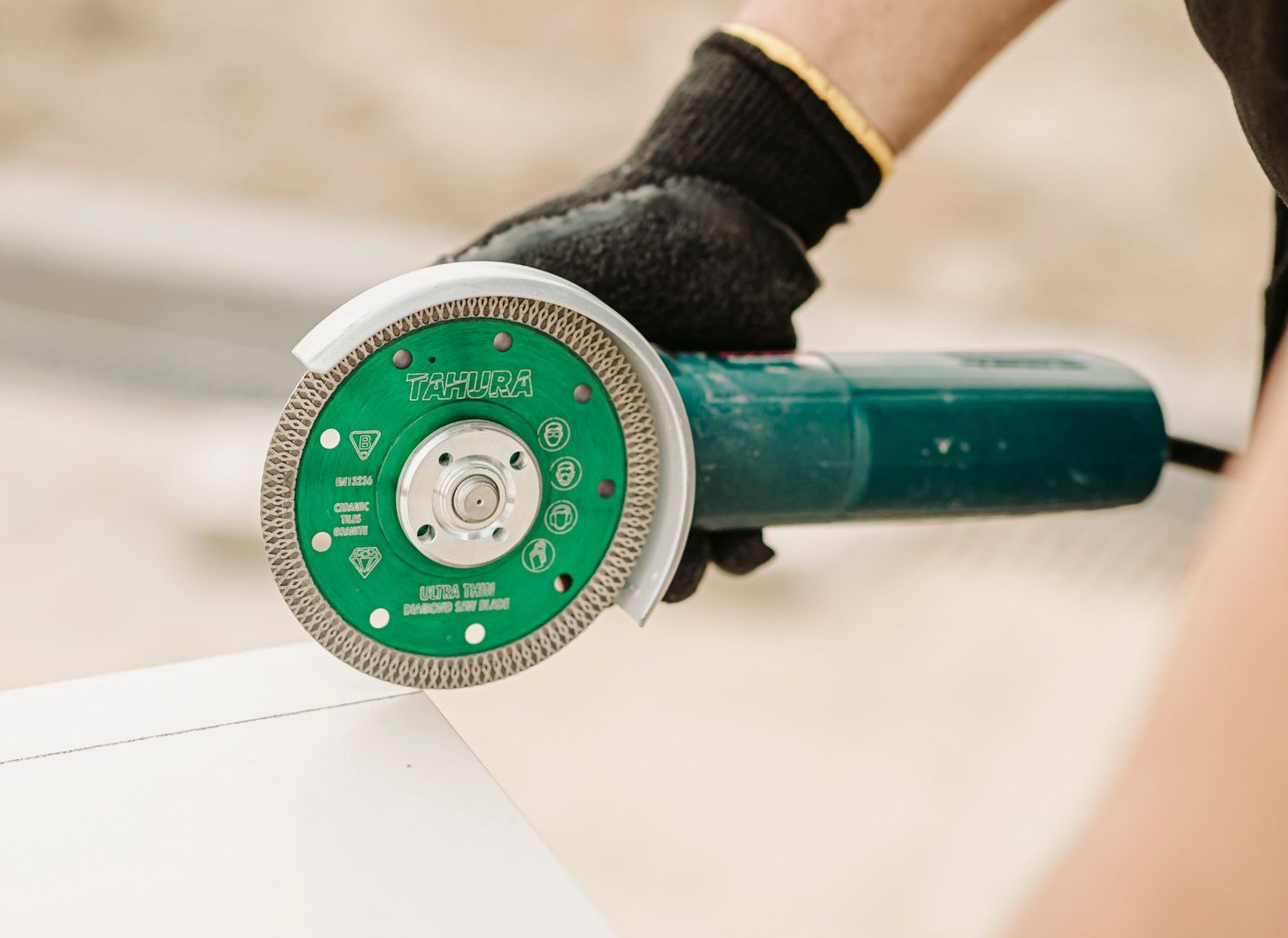 Angle grinder fitted with a green turbo-rim diamond blade, a finer-edged diamond blade for pavers and stone