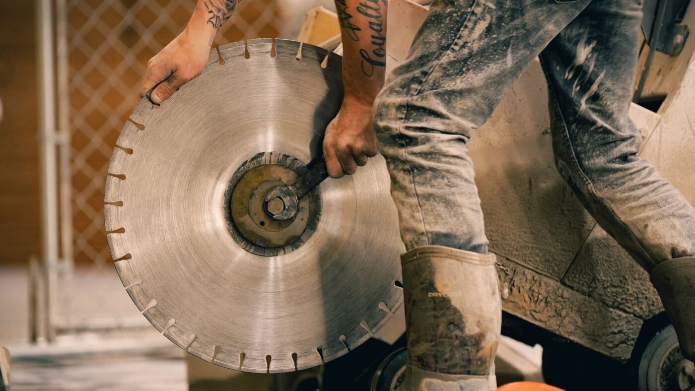 Worker fitting a large segmented diamond saw blade, the kind of diamond blade used for cutting concrete and pavers