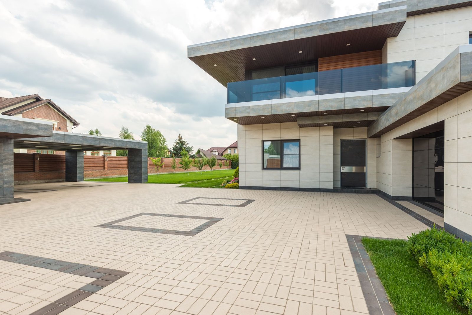 Paver driveway with a dark contrasting border course separating the light field pavers from the lawn