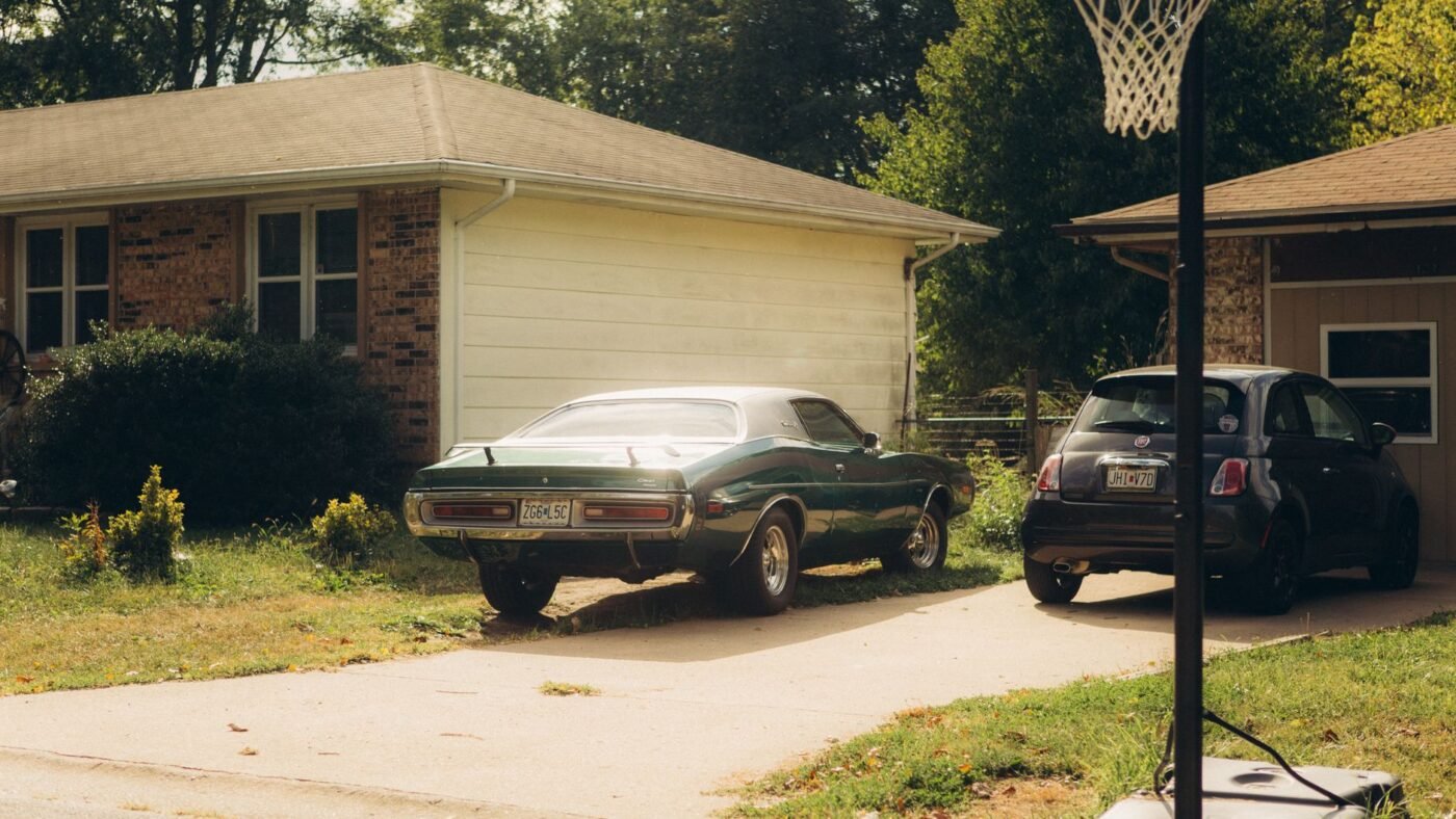 Car parked on the lawn beside a narrow concrete driveway, a common reason to add a driveway paver extension