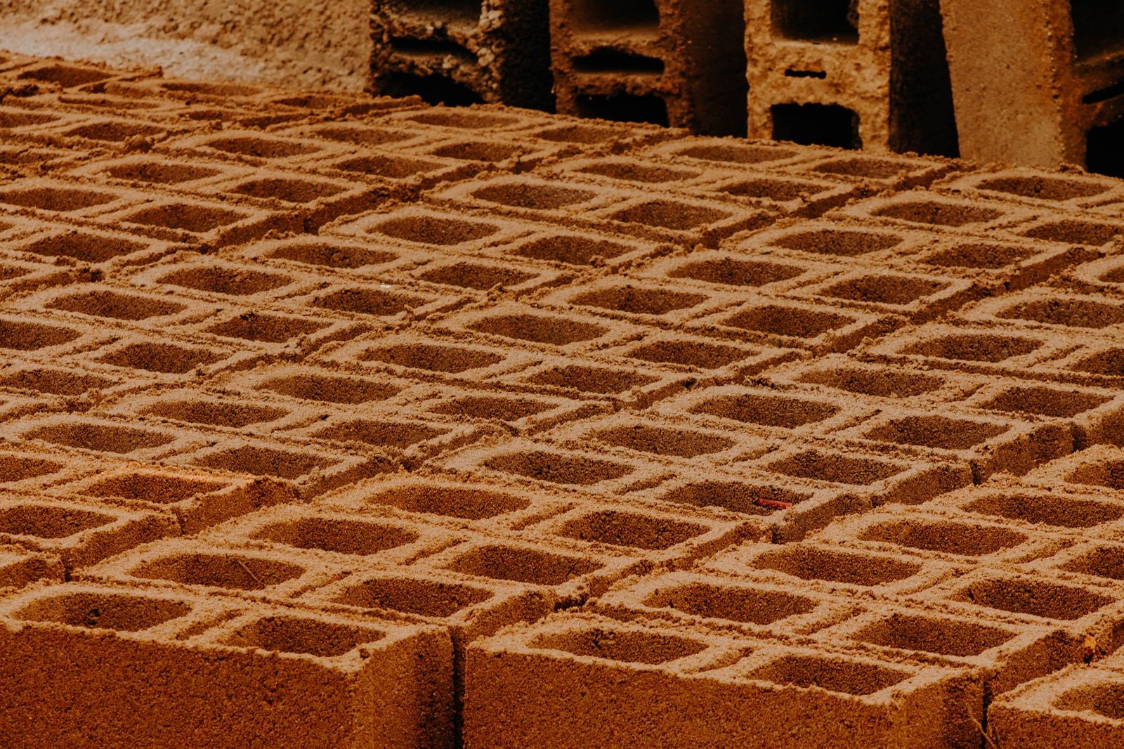 Rows of hollow concrete cinder blocks stacked at a supply yard, a cheap but crack-prone option for a fire pit