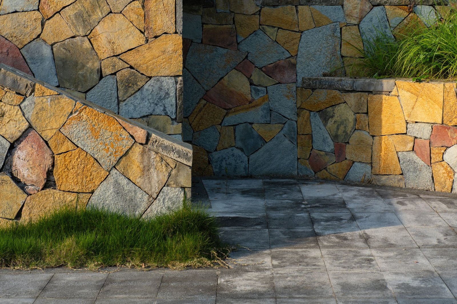 Natural stone retaining walls and a paved courtyard floor, both examples of hardscape, with a strip of grass along the edge