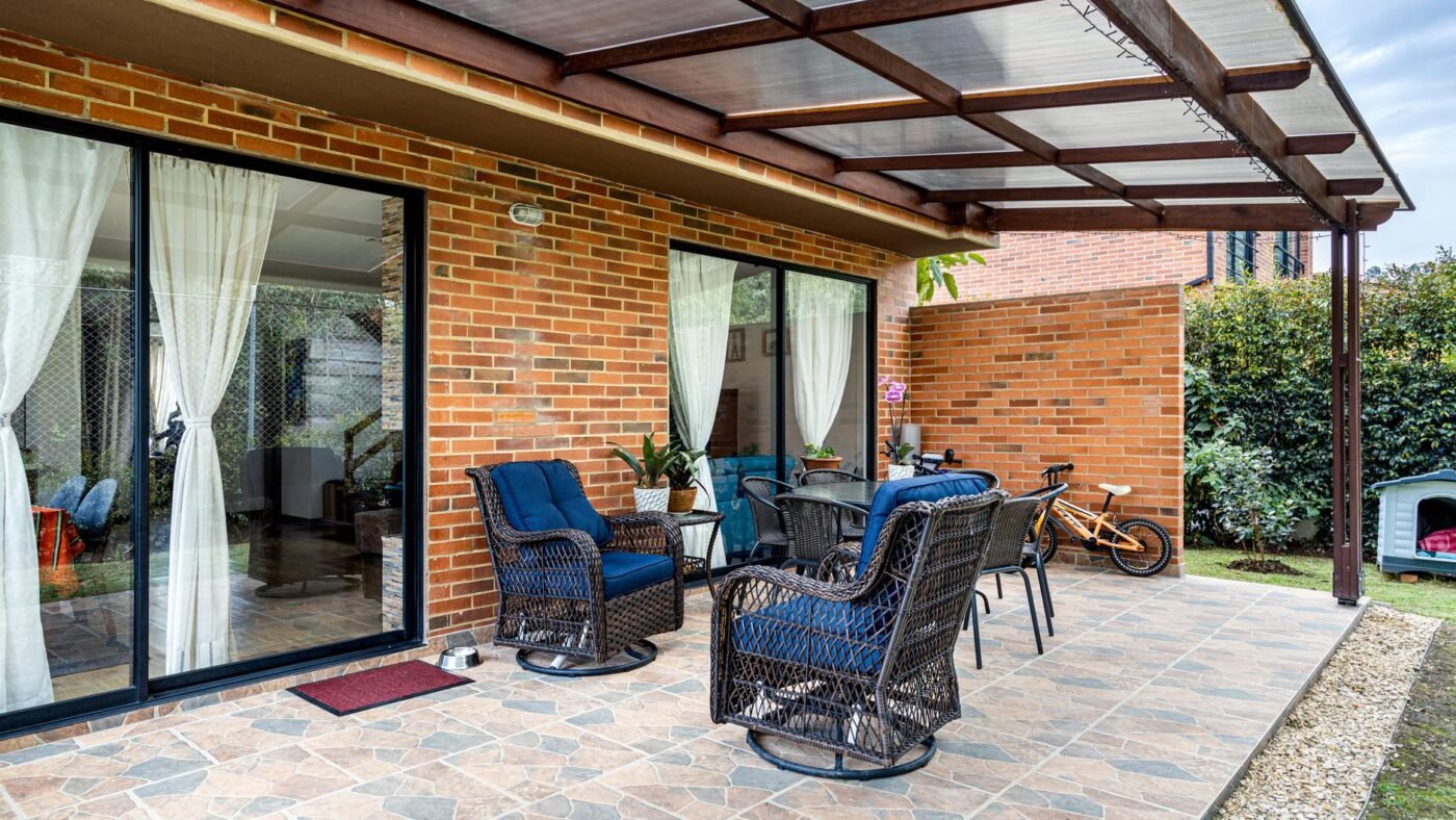 Covered paver patio with blue wicker armchairs against a brick house, furniture that goes back only after the paver sealer has cured