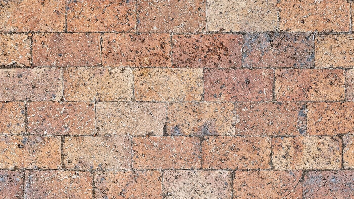 Clay brick pavers in running bond with narrow filled joints on a dry, sunny day