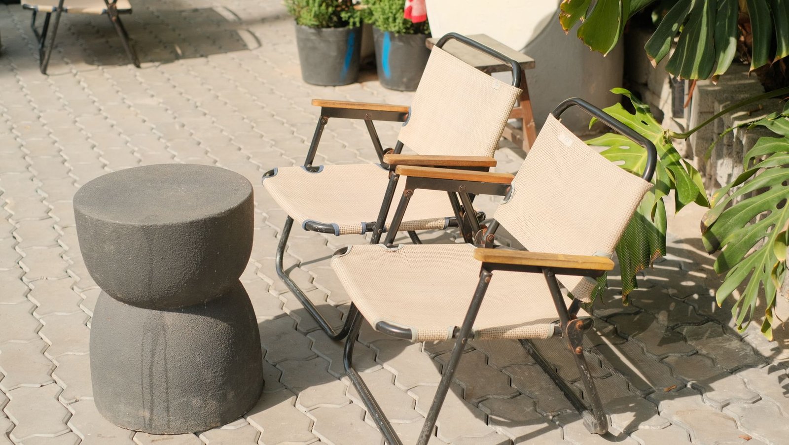 Grey concrete pavers under outdoor chairs in hard sunlight, showing the UV exposure that wears paver sealer and shortens the time between reseals