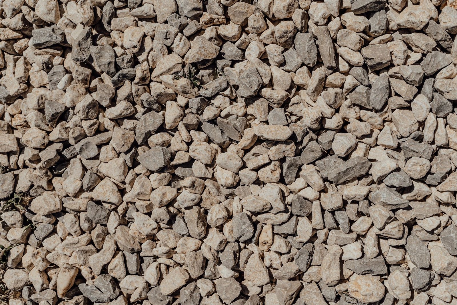 Close-up of angular crushed stone with sharp broken faces, the kind of gravel that compacts into a solid base