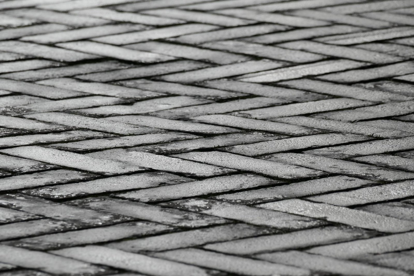 Close-up of paving stones laid in a herringbone pattern, a layout where every edge paver has to be cut