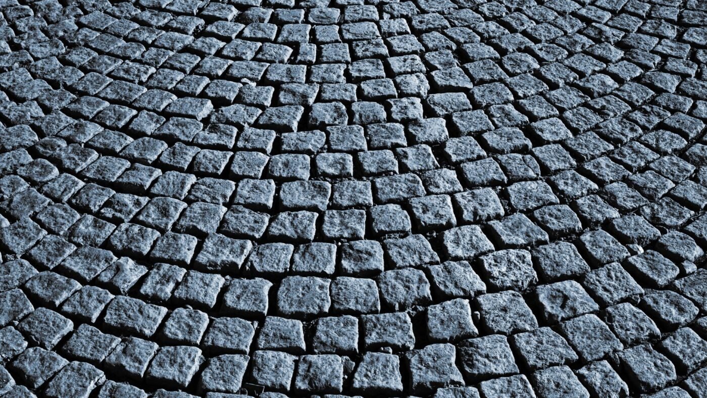 Small square cobblestone pavers laid in sweeping arcs, a pattern that follows curves with few cuts