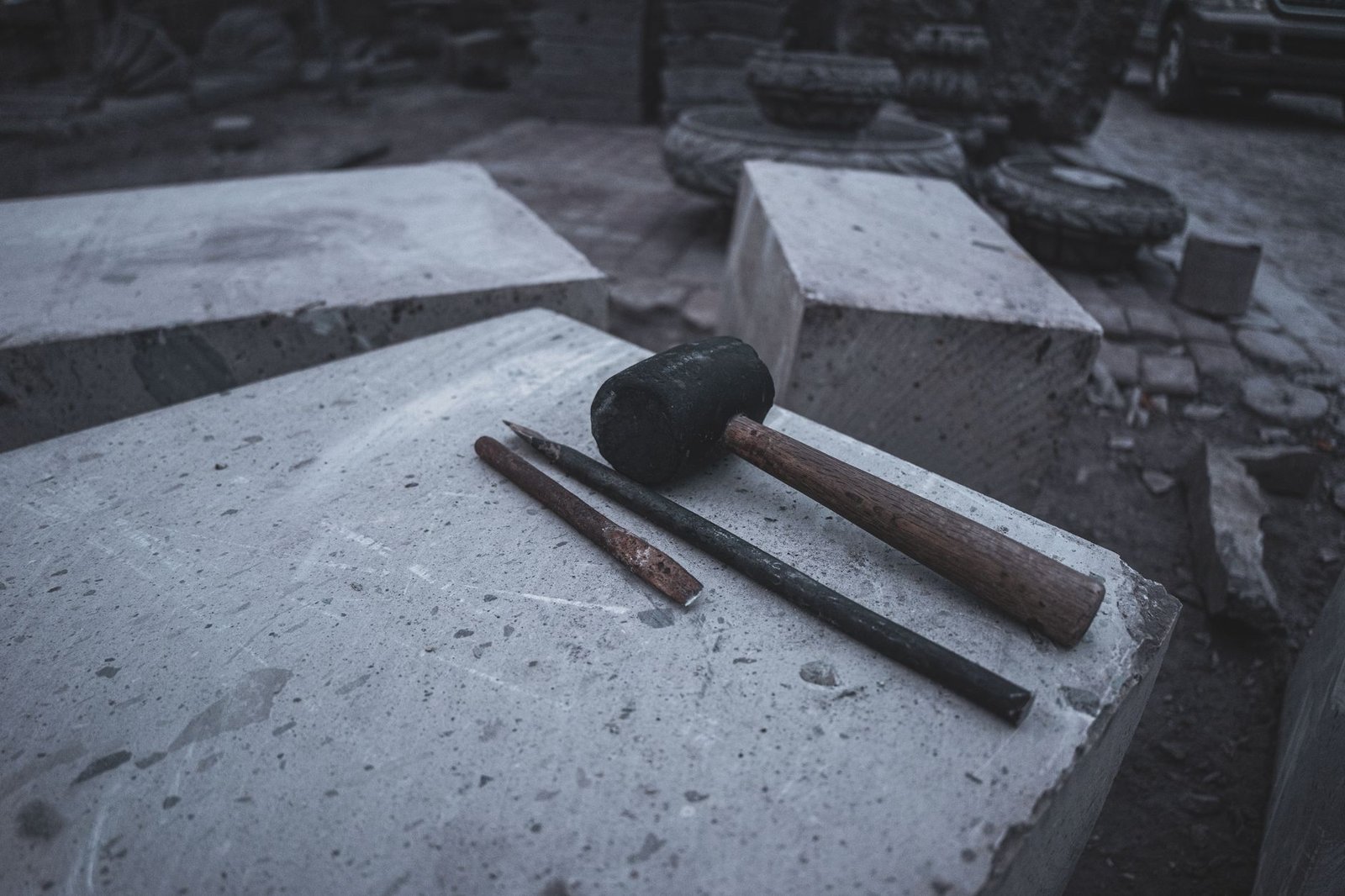 Rubber mallet and two steel chisels lying on a concrete block, the basic kit for cutting pavers by hand
