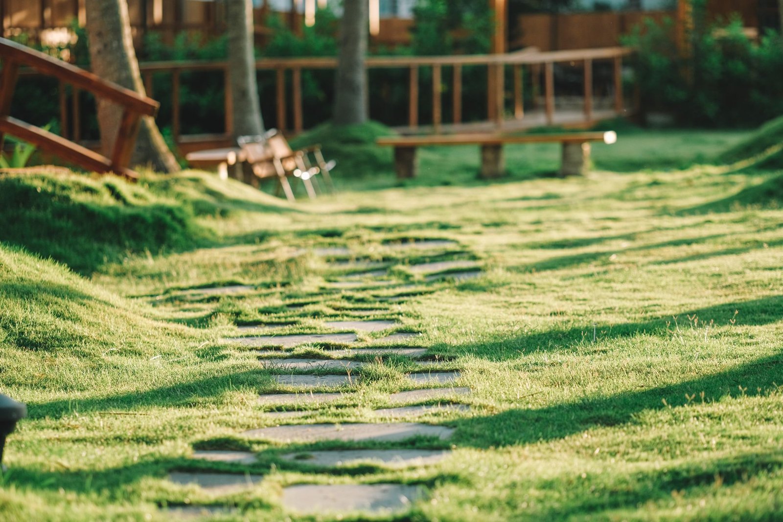 Flat stepping stones sitting flush in a mowed lawn with grass growing up to their edges
