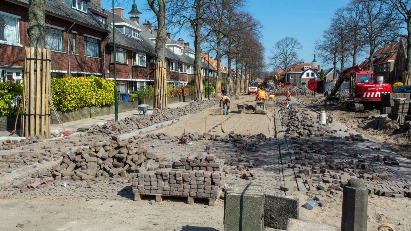 Residential street with its brick pavers pulled up and stacked on pallets for reuse while the base is rebuilt