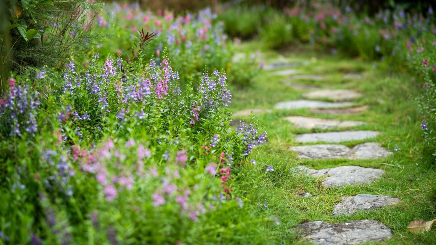 Flat stone pavers set directly into the soil along a grassy garden path lined with flowers