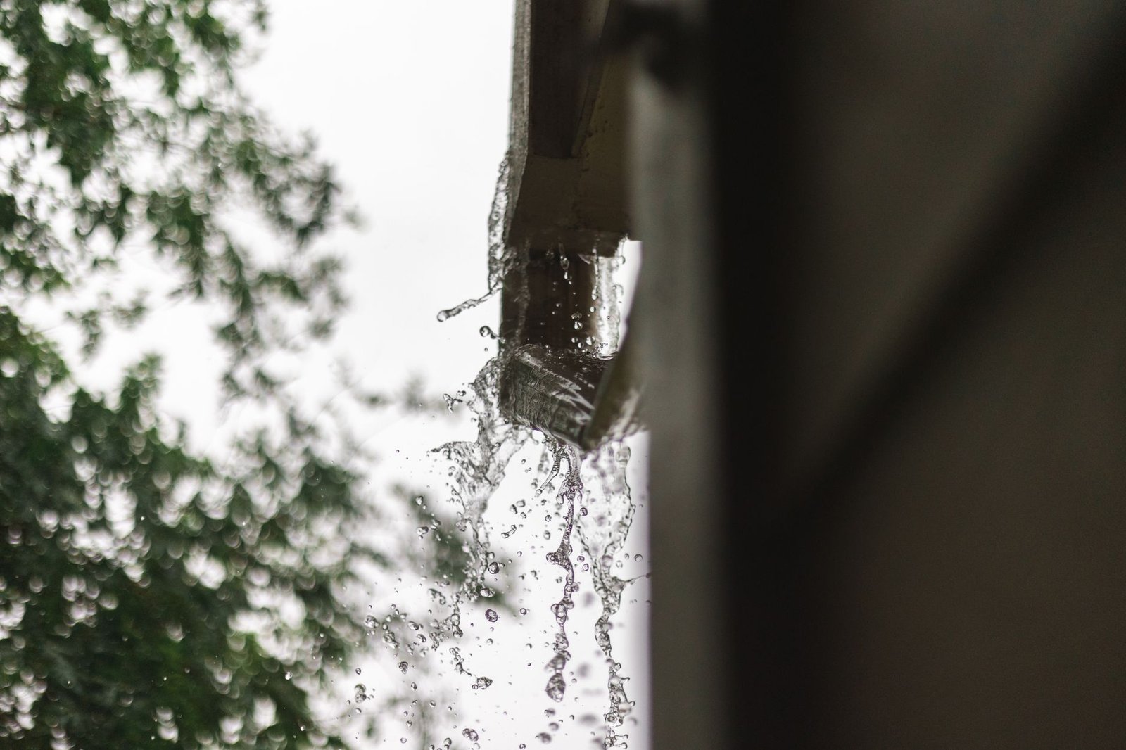 Rainwater pouring out of a downspout during a storm, roof runoff that must be routed away from a patio