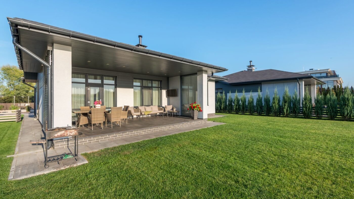 Backyard paver patio under a covered porch where the patio edge meets a trimmed lawn