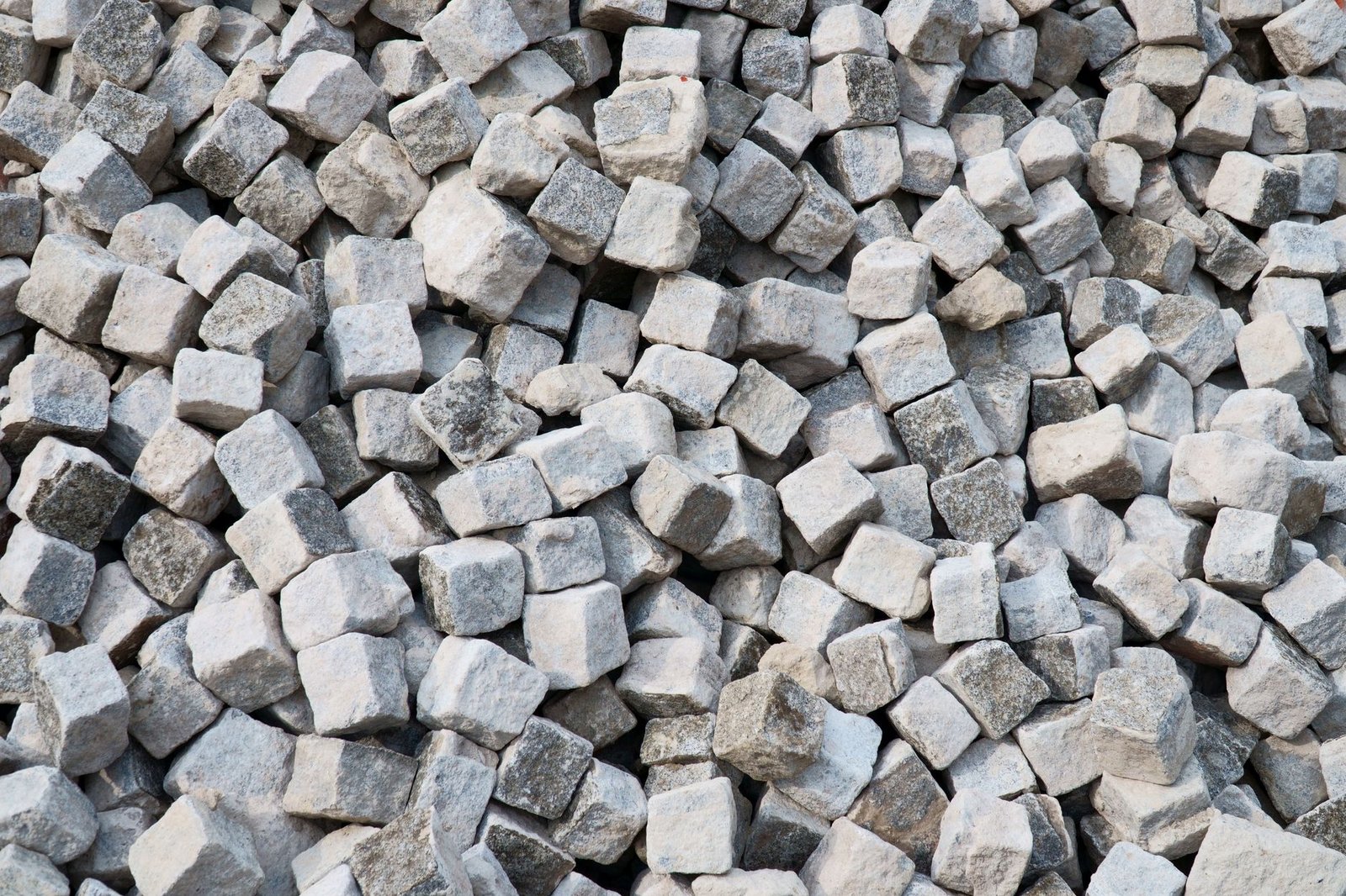 Pile of rough gray granite cobblestones, a natural stone option at the upper end of patio paver prices