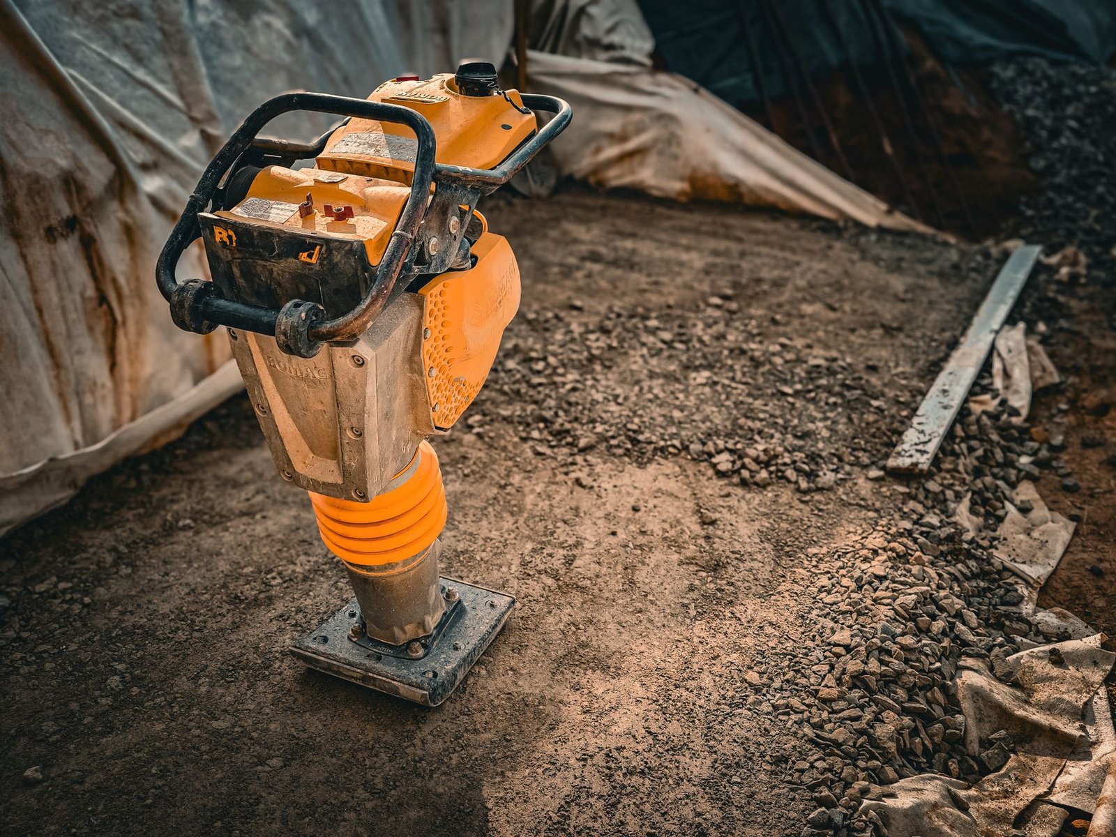 Vibratory rammer compactor on a gravel base, used to compact paver base stone in thin lifts