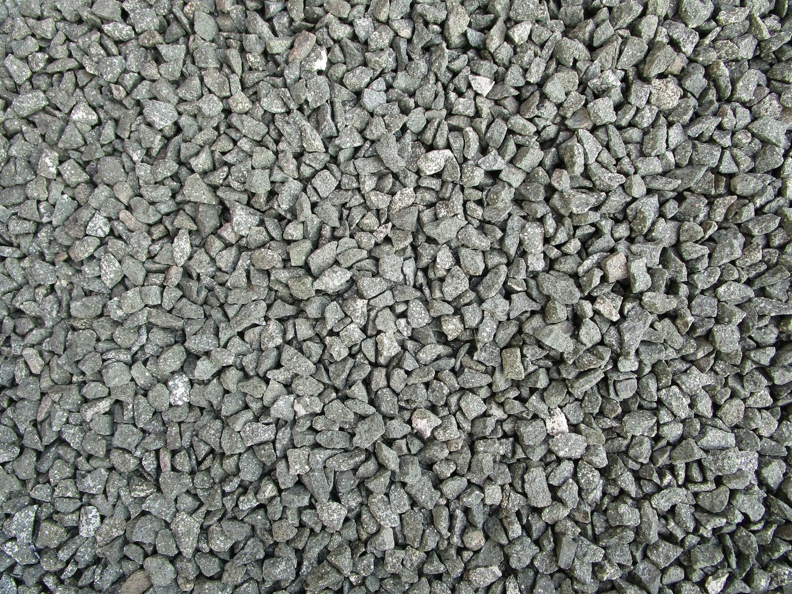 Close-up of angular gray crushed stone, the type of dense-graded gravel used for a compacted paver base