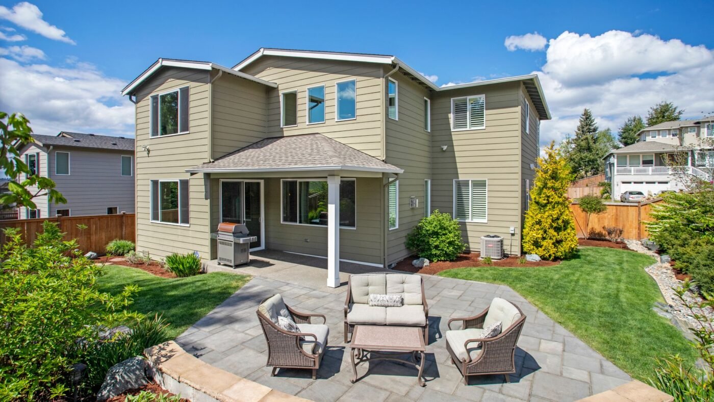 Finished paver patio beside a house, built on a compacted paver base that slopes away from the foundation