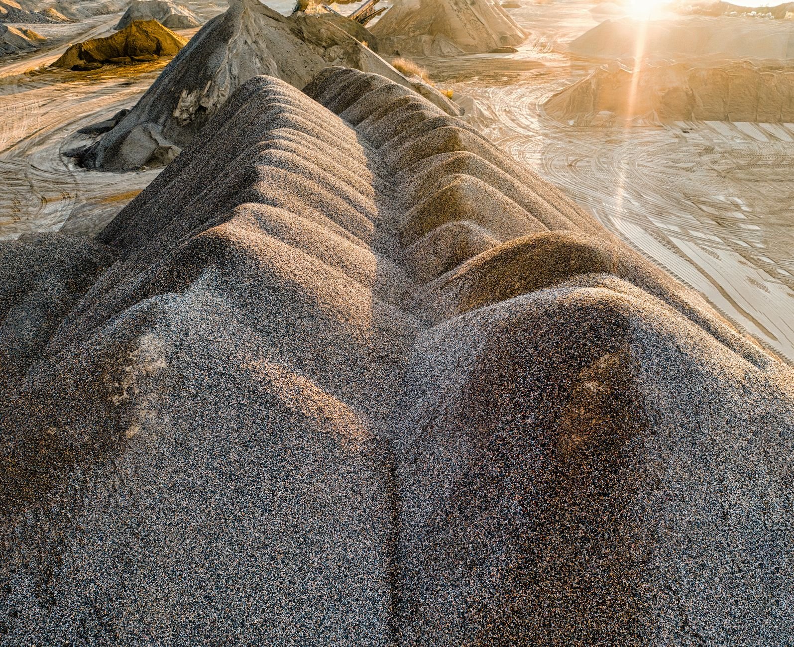 Stockpiles of crushed aggregate at a quarry, where bulk paver base material is bought by the ton