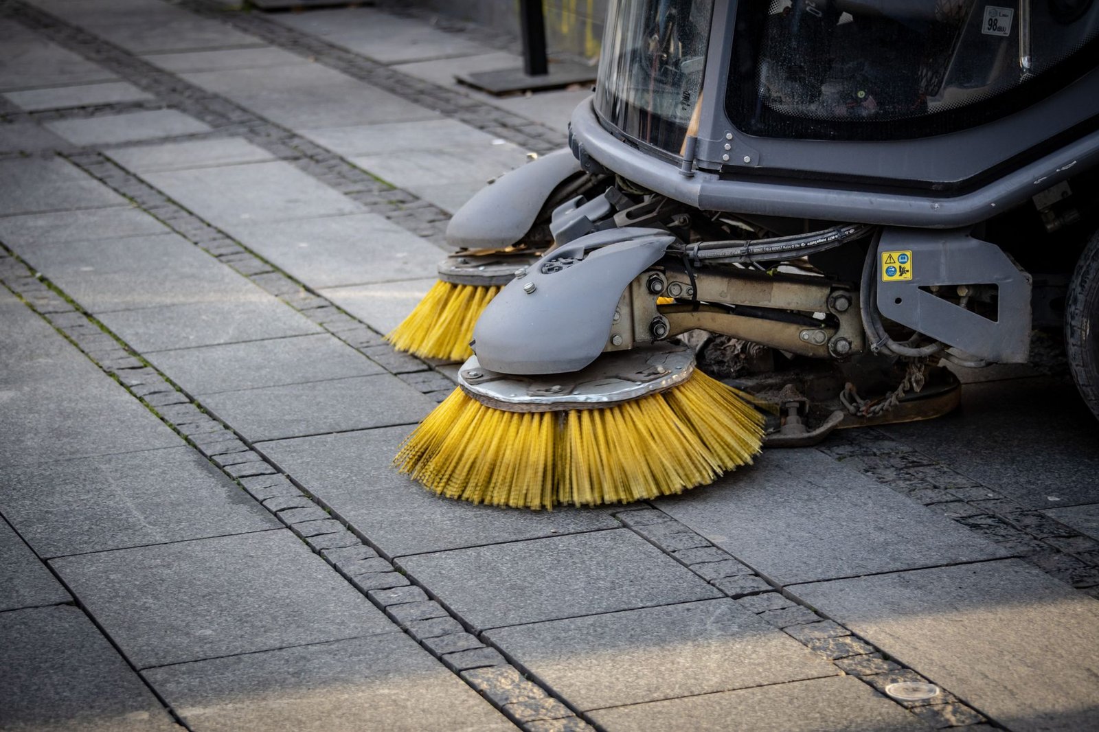 Rotating brushes of a mechanical sweeper scrubbing a paved surface