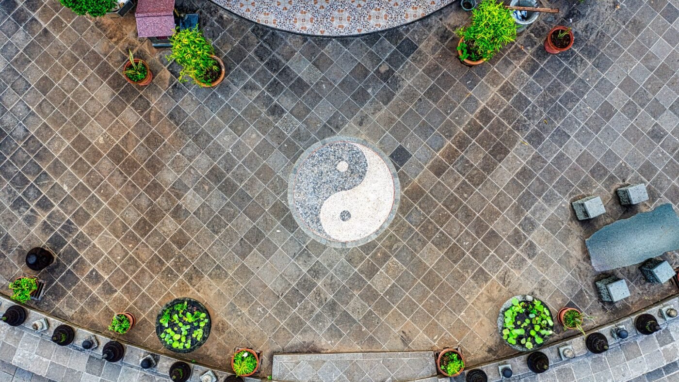 Overhead view of a clean paver patio laid on the diagonal, with potted plants around the edge