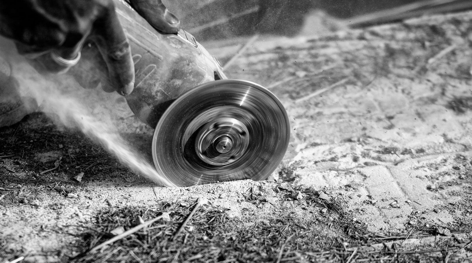 Close-up of an angle grinder with a diamond blade cutting into a stone surface and throwing fine dust