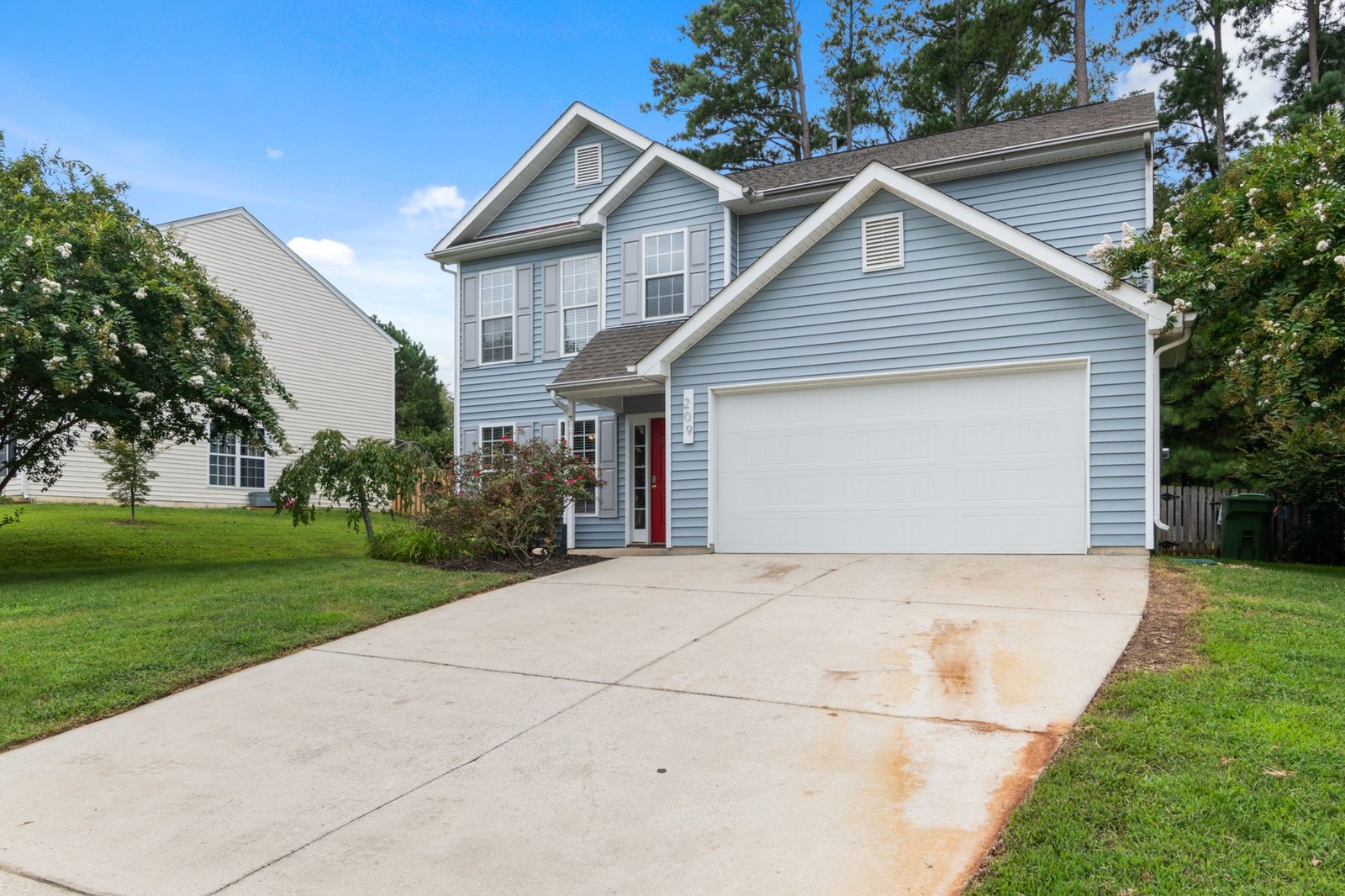 Plain poured concrete driveway with rust stains leading to a two-car garage