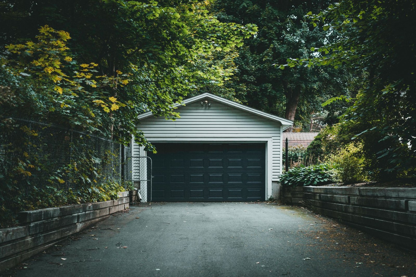 Asphalt driveway leading to a detached garage between low retaining walls