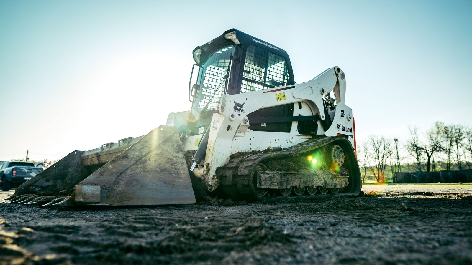 Tracked skid steer loader with bucket on a bare dirt site ready for excavation