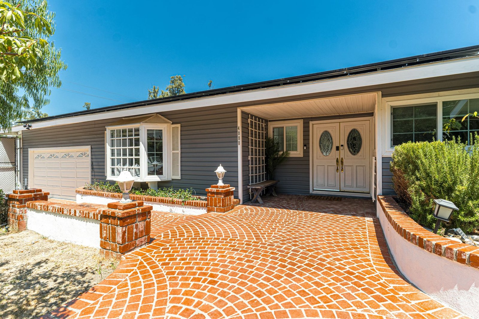 Red brick paver driveway laid in a fan pattern leading up to a single-story house