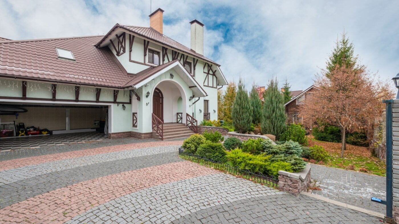 Finished paver driveway in two-tone cobble pavers leading to a house and open garage