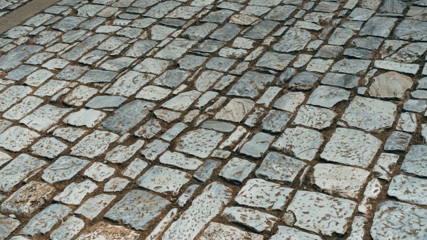 Granite cobblestone paving with wide, irregular sand-filled joints, the kind of joint a resin paver joint compound is made for