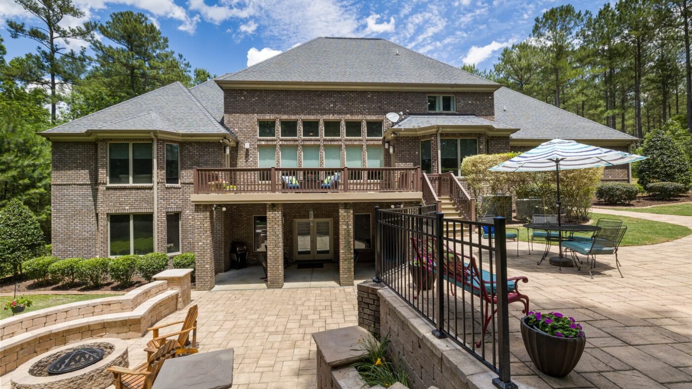 Brick house on a sloped lot with a lower paver patio, a raised upper paver patio, block retaining walls and steps between the levels