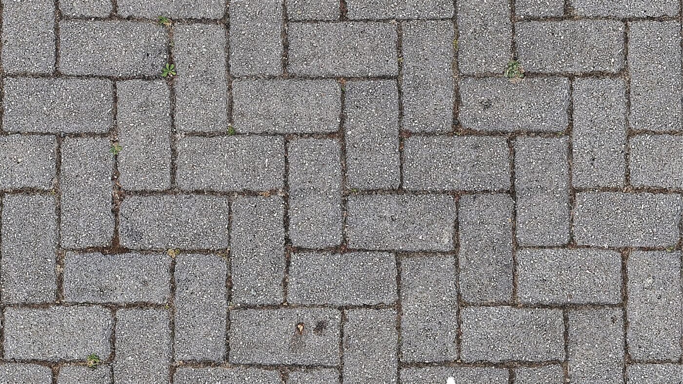 Gray concrete paving stones laid in a 90 degree herringbone paver pattern, seen from directly above