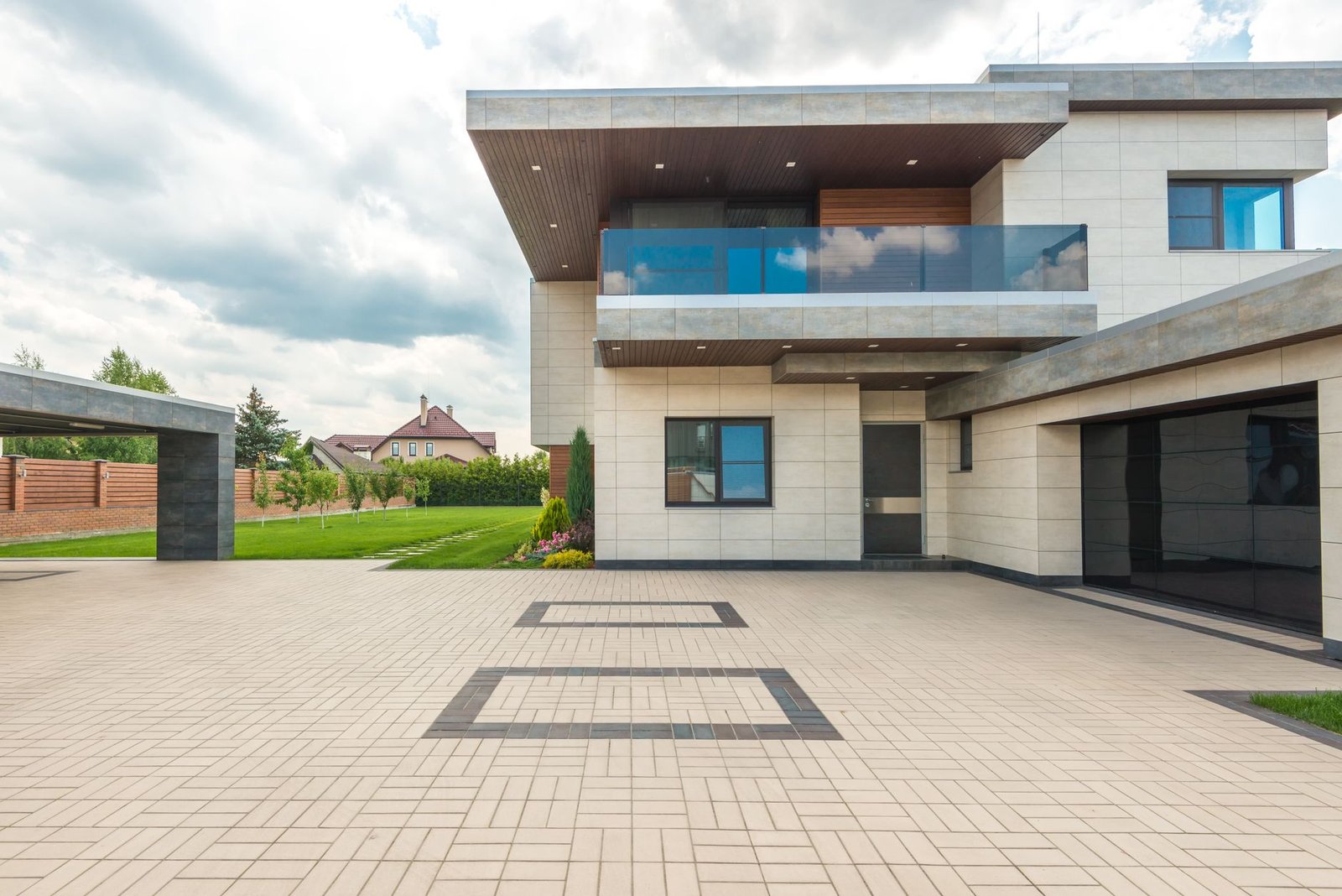 Large-format concrete paver driveway in front of a modern two-story house, a high-traffic surface where sealing driveway pavers pays off