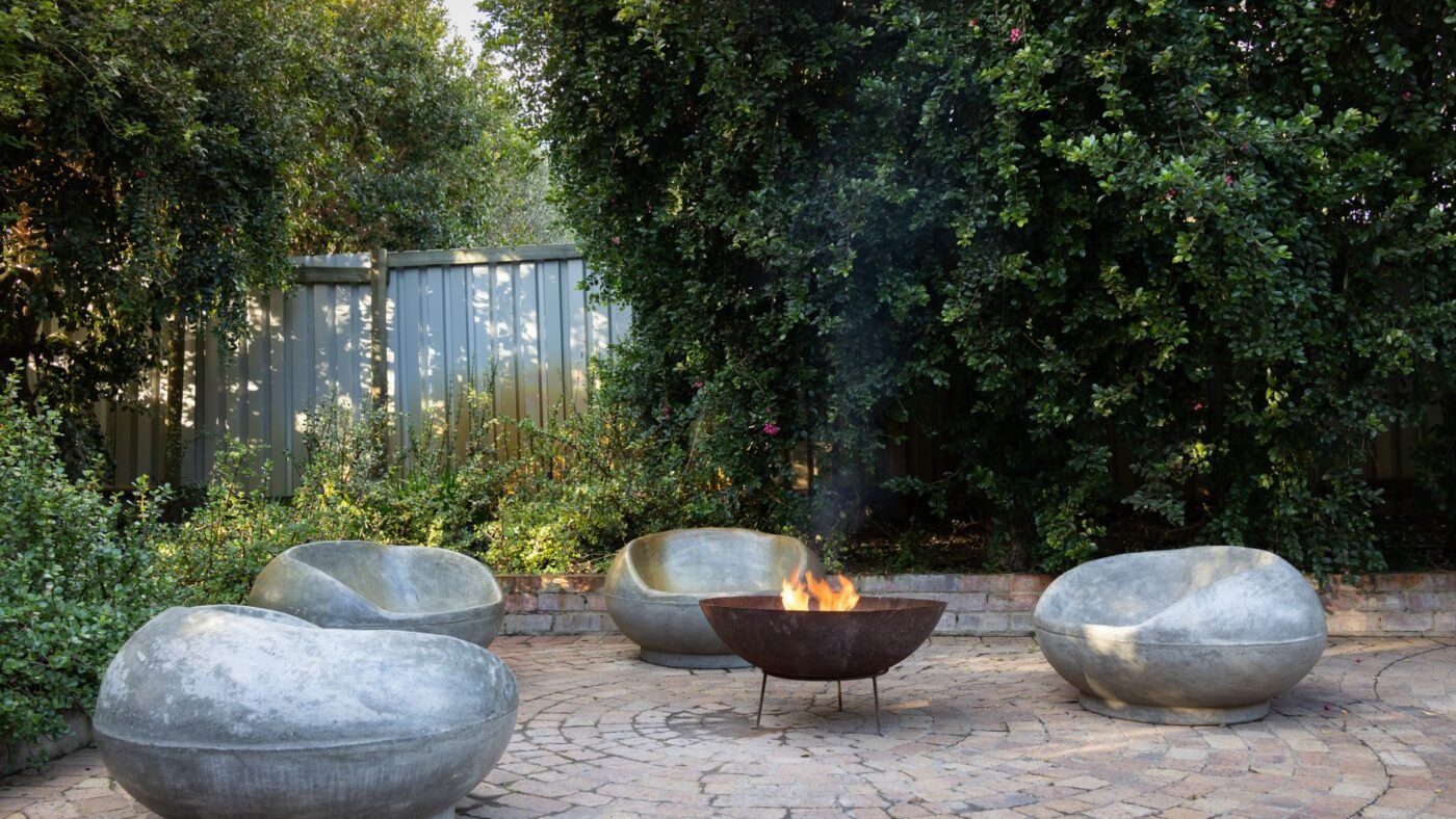 Circular tumbled paver patio with a fire bowl and stone seats, the kind of concrete paver surface homeowners seal against stains and fading