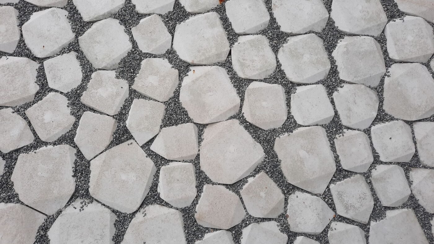 Top view of pale stone pavers set in a bed of fine gray gravel, forming a paver and gravel walkway surface