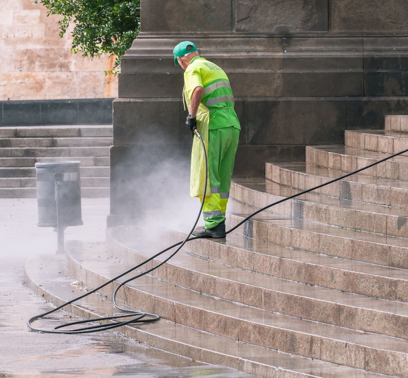Worker pressure washing stone steps, the cleaning step before laying pavers over a concrete patio