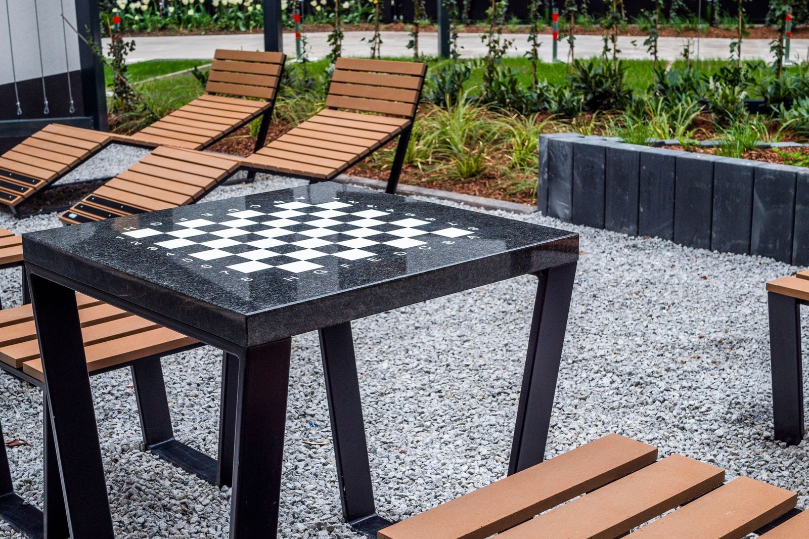 Gravel seating area with a row of dark concrete blocks set as a firm edge between the gravel and a planting bed