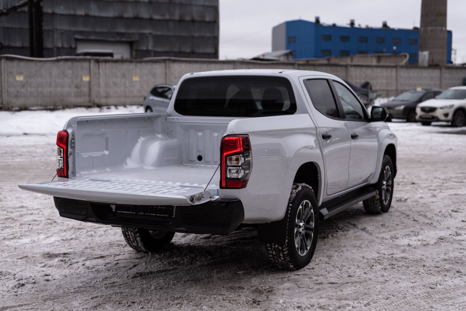 White pickup truck with its tailgate down and an empty cargo bed, ready to haul a rented plate compactor