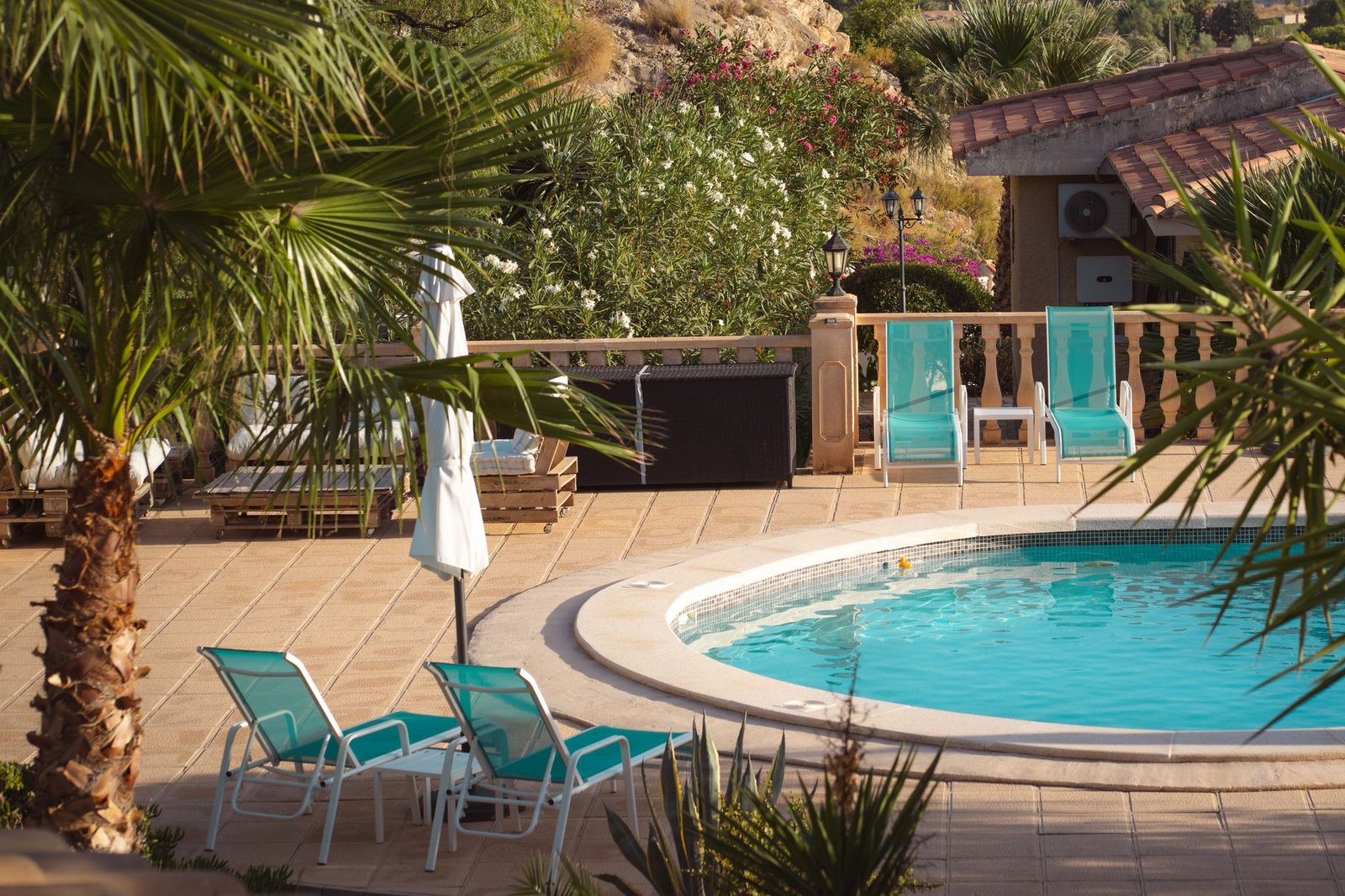 Pool deck of square tan pavers around a curved swimming pool with lounge chairs, where a natural penetrating paver sealer keeps barefoot grip