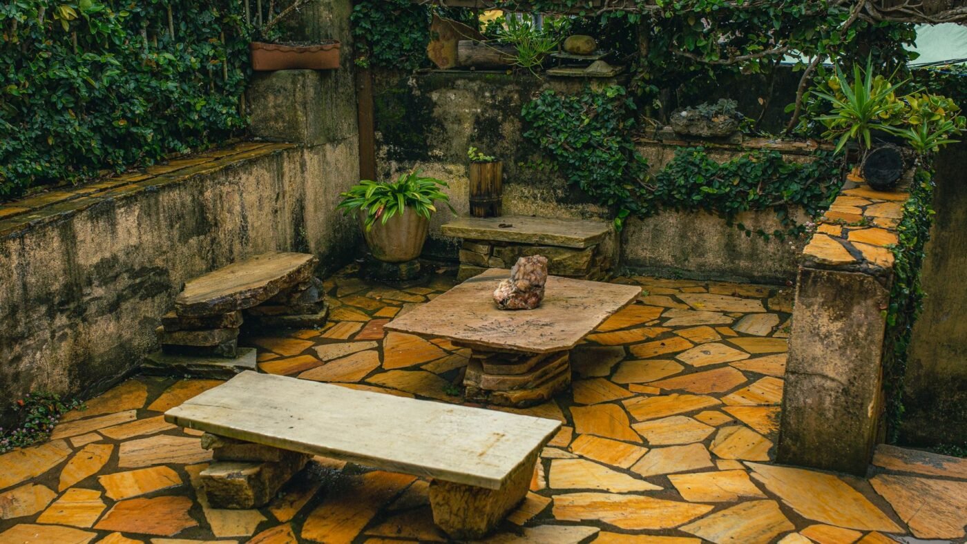 Sunlit flagstone patio in golden and orange tones with stone benches and ivy-covered walls, the kind of natural color a paver sealer finish either deepens or preserves