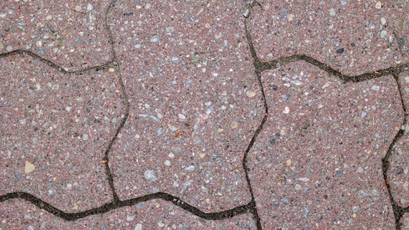 Close-up of interlocking red concrete pavers with narrow, tightly filled joints, the kind of joint polymeric sand is made for